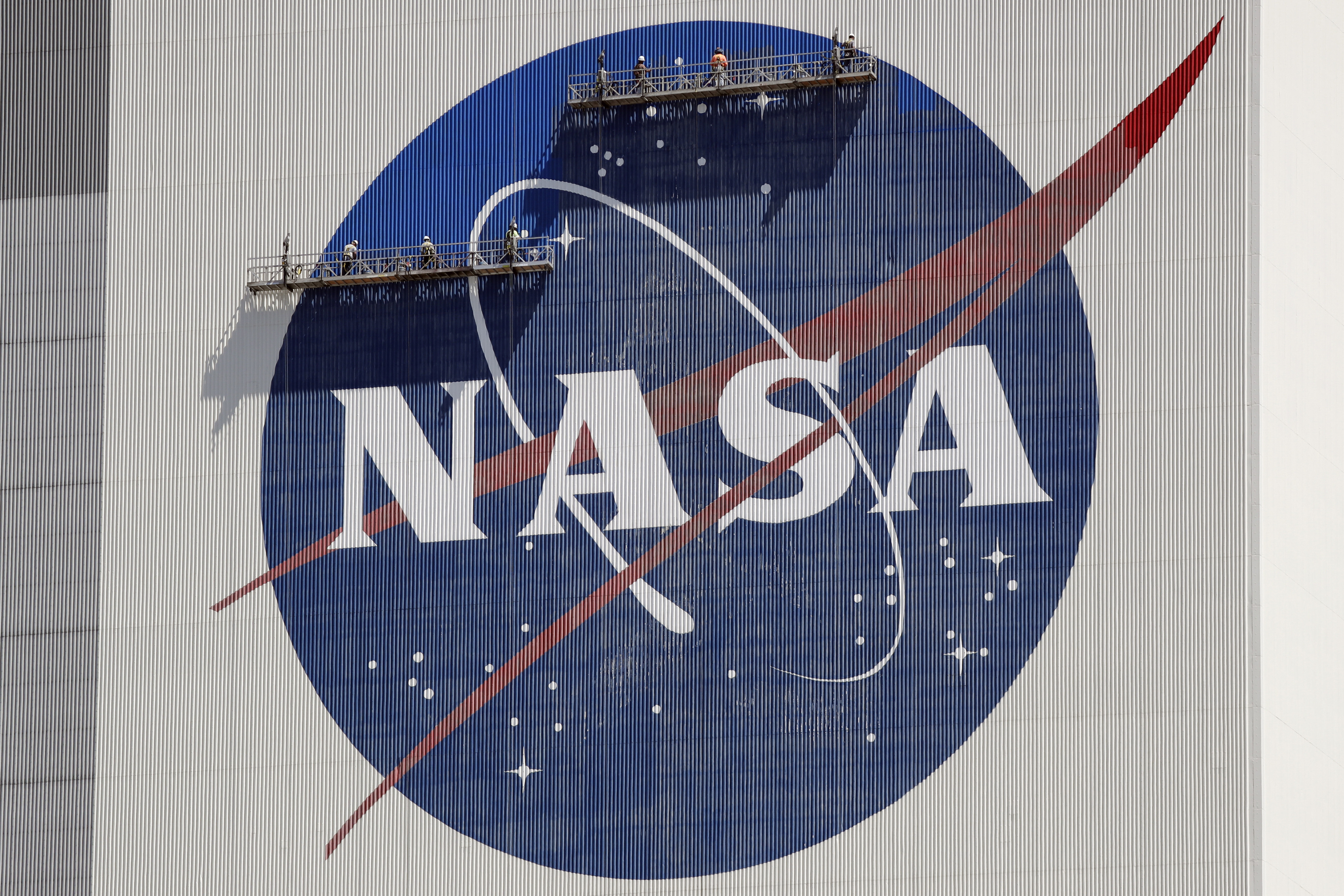脚手架上的工人重新粉刷靠近飞行器组件顶部的 NASA 徽标肯尼迪航天中心大楼